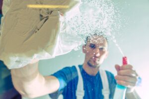 Men Cleaning Office Windows. Windows Detergent Spraying and Cleaning by Caucasian Male. Cleaning Service Worker.